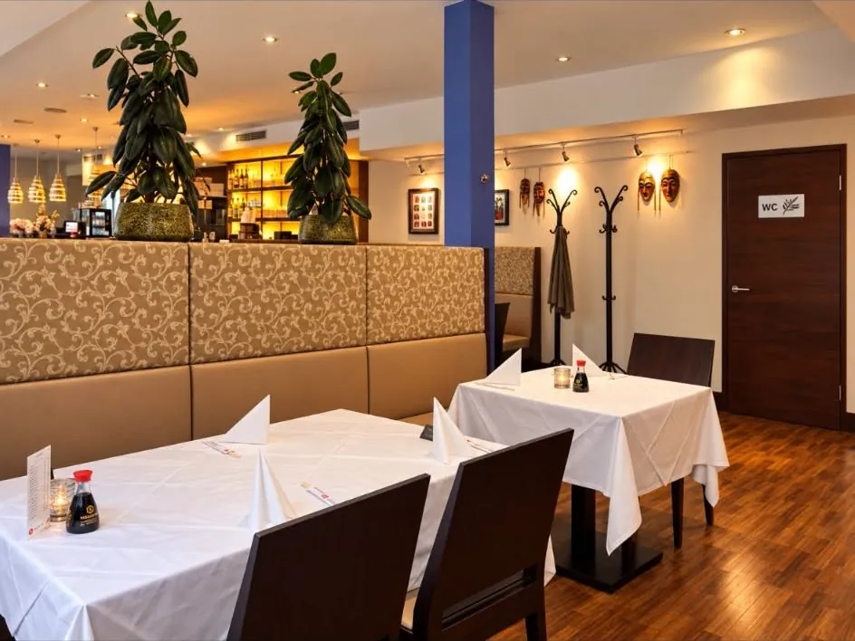 Gastraum mit Bank-Bestuhlung vor der Bar, Masken an der Wand