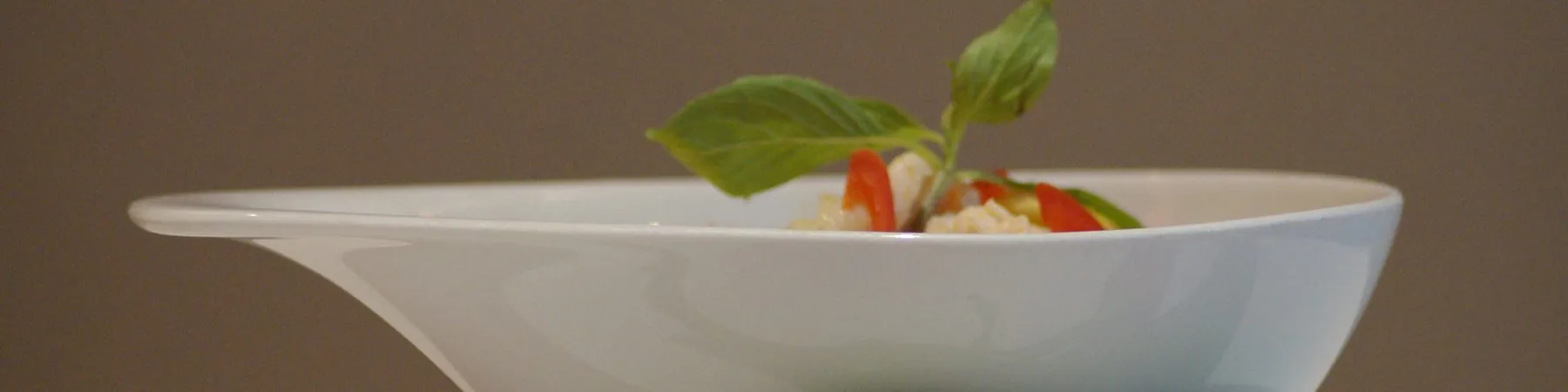 Suppe in weißer Schale, mit frischem Basilikum angerichtet