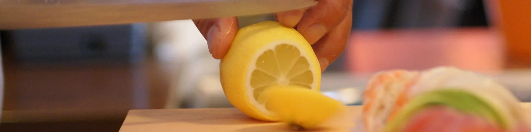 Der Koch richtet Sushi mit frischer Zitrone auf dem Holzbrett an